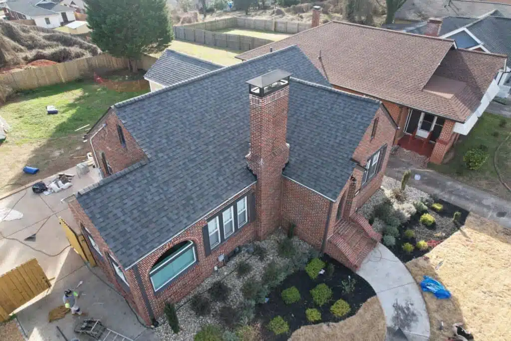 High-quality asphalt shingle roofing on a classic brick house with a prominent chimney.