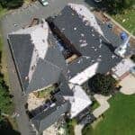 Aerial view of church roof restoration, showing roofing workers replacing shingles and inspecting for damage.
