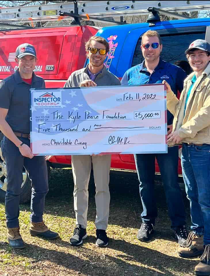 Expert roofing company inspection team with a charitable donation check.